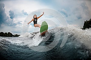 Young girl stunts on a wakeboard in the river near forest