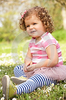 Young Girl In Summer Dress Sitting In Field