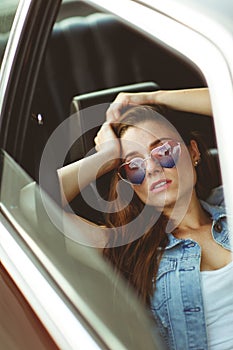 Young girl in sunglasses sitting in car, tinted photo