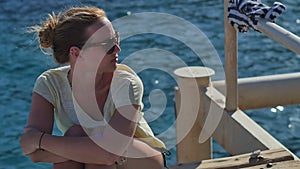 Young girl in sunglasses sitting near the seashore on a sunny day