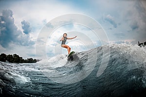 Young girl surfs on a wakeboard in the river near forest