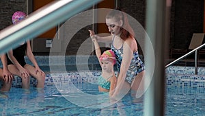 A young girl swimming coach teaches young children to swim.