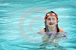 Young Girl Swimming in Pool with Orange Goggles