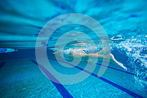 Young girl swimming underwater in pool