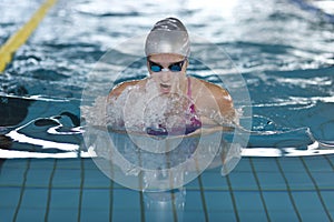 Young girl swims breaststroke in the swimming pool