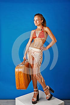 Young girl in swimsuit holding a suitcase.