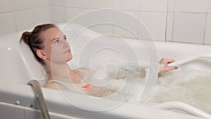 A young girl in a swimsuit spends time in the Spa, lying in the bathroom with hydromassage