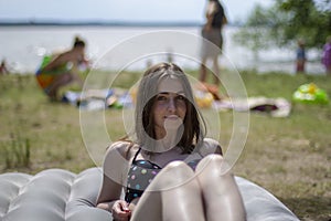 A young girl in a swimsuit sunbathes on the seashore on an air mattress