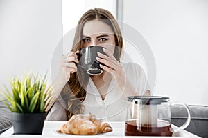 A Young Girl take Breakfast in Bed. French Croissants With Tea on a Tray
