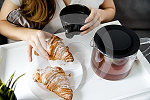 A Young Girl take Breakfast in Bed. French Croissants With Tea on a Tray