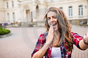 Young girl take selfie from hands with phone with smile on summer city street urban life concept