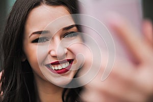 Young girl take selfie from hands with phone on summer city street. Urban life concept