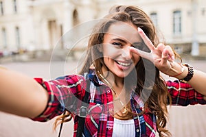 Young girl take selfie from hands with phone with victory sign o