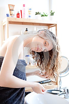 Young girl taking care of her hairs in a bathroom