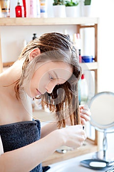 Young girl taking care of her hairs in a bathroom