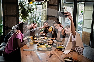 Young girl taking a photo with her friends in a cafe