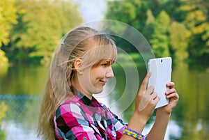 Young girl taking photo of the lake by tablet pc