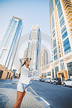 Young girl taking photo of skyscrapers background. Attractive girl photographer shoots on camera views of the city