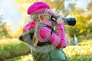 Young girl taking photos in autumn park