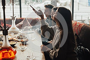 Young company is having fun and eating in bar. smoking a hookah, communicating in an oriental restaurant.