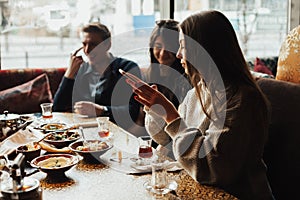 Young company is having fun and eating in bar. smoking a hookah, communicating in an oriental restaurant.