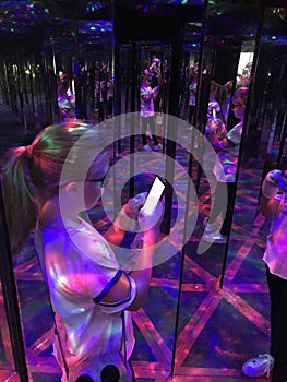 A young girl taking a selfie in hall of mirrors