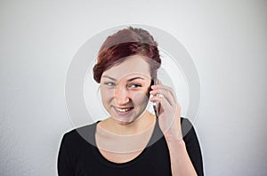 A young girl talking on a cell phone with a smile on her face, a white background, facial expressions