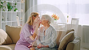Young girl talking an elderly woman in the ear of on the couch