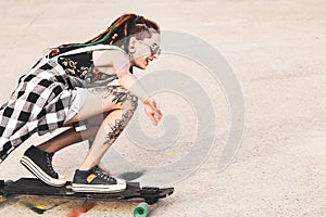 Young girl with tattoo rides on a longboard