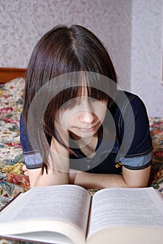 The young girl the teenager lies on a bed with the book. She was fond of reading.