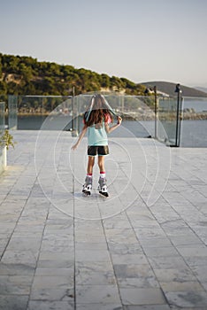 Young girl, teenager, rollerblading near the sea. Green T-shirt, colored hair. Funtime photo