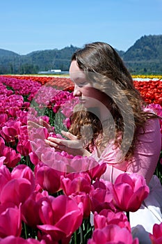a young girl teenager stands in beautiful bright pink Corolla tulips inhale the fragrance of flowers straighten her hair