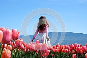 a young girl teenager stands in beautiful bright pink Corolla tulips inhale the fragrance of flowers straighten her hair