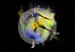 Young girl tennis player in explosion of colored neon powder isolated on dark background. Purple and yellow