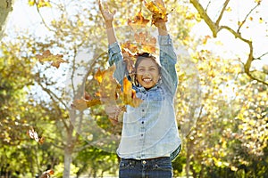 Young Girl Throwing Autumn Leaves In The Air