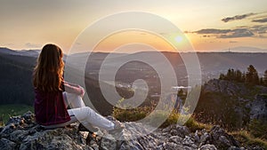 Young girl tourist looks at sunset over Zakopane from the top of the mountain, Poland, High Tatras