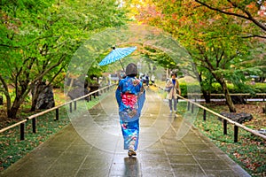 Young girl tourist wearing blue kimono and umbrella took a walk in park