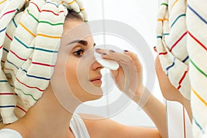 Young girl with towel on hair wipes his nose with a cotton disk