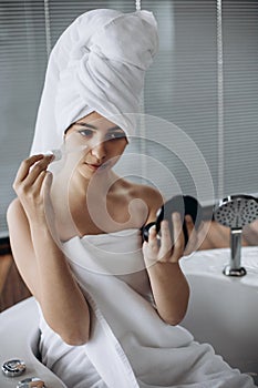 Young girl with towel on her head makes facial treatments. Skin care, moisturizing with serum