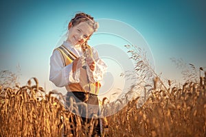 Young girl with traditional Bulgarian folklore costume at the agricultural wheat field during harvest time with industrial combine