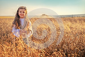 Young girl with traditional Bulgarian folklore costume at the agricultural wheat field during harvest time with industrial combine