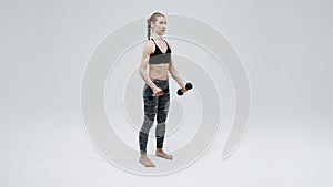 Young girl trainer performs synchronous exercises with dumbbells  to strengthen muscles.