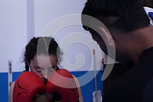 Young girl training boxing in a gym with her trainer