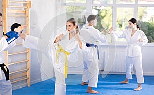 Young girl training kicks on punch mitts held by instructor photo