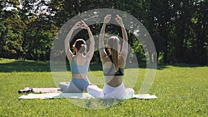 Young girl training outdoors in early summer morning, in park, doing yoga and stretching exercises. Toned body and mind