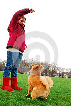 A young girl trains her dog to sit and jump