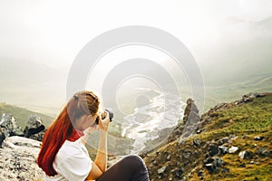 A young girl traveler takes pictures of a summer mountain landscape. Elbrus region, Russia. Woman Emancipation Concept