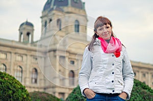 Young girl traveler with white jacket and red scarf looking at camera and posing, Kunsthistorisches Museum