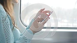 Young girl traveling in a train and using mobile phone. Beautiful woman sends a message from the smartphone. Attractive