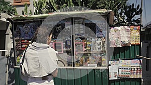 Young girl traveller chooses a postcard and asia souvenirs